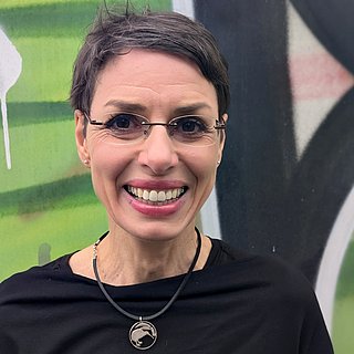 Frau mit Brille und kurzen dunklen Haaren