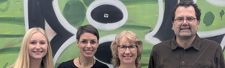 drei Frauen und ein Mann stehen nebeneinander